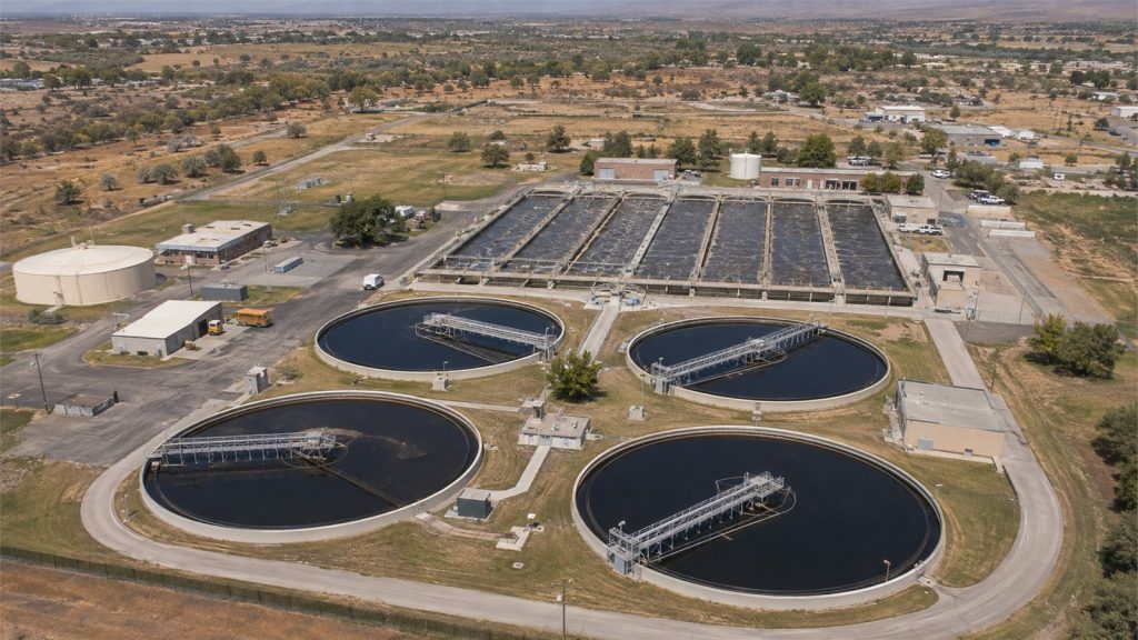 Aerial view of a municipal wastewater treatment plant with clarifiers and aeration basins.